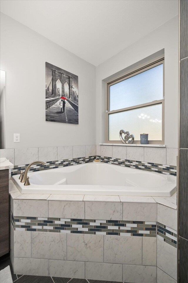 bathroom featuring vanity and tiled bath