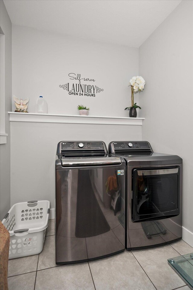 laundry room with light tile patterned flooring and washer and clothes dryer