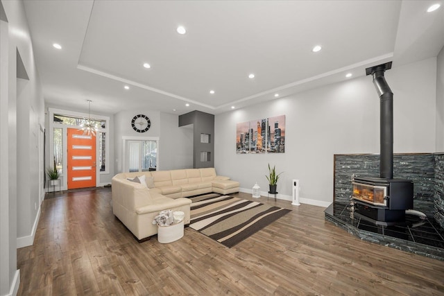 living room with hardwood / wood-style flooring, a raised ceiling, and a wood stove