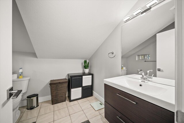 bathroom with tile patterned flooring, vanity, vaulted ceiling, and toilet