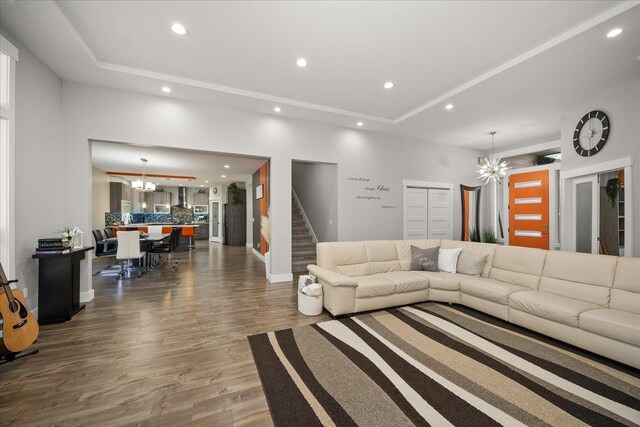 living room with a raised ceiling, dark wood-type flooring, and a notable chandelier