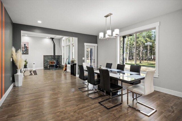 dining space featuring dark hardwood / wood-style floors, a wood stove, and a notable chandelier