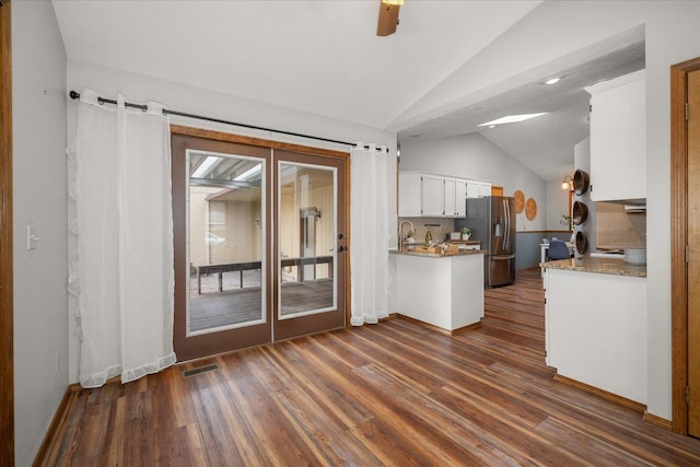 kitchen with white cabinetry, vaulted ceiling, stainless steel fridge with ice dispenser, dark hardwood / wood-style floors, and light stone countertops