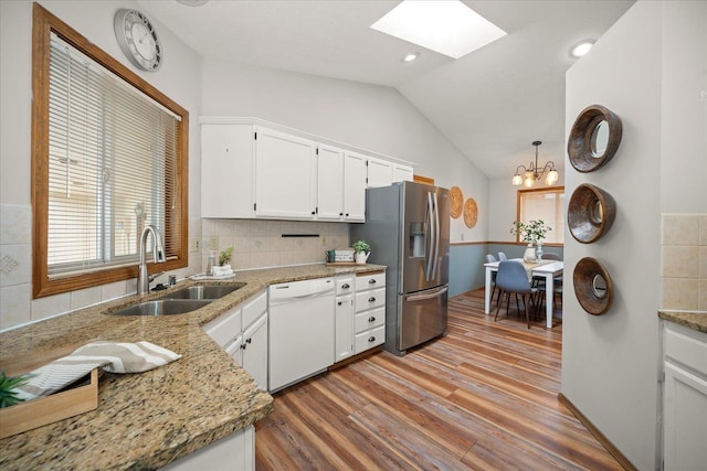 kitchen with pendant lighting, sink, stainless steel fridge, white cabinets, and white dishwasher