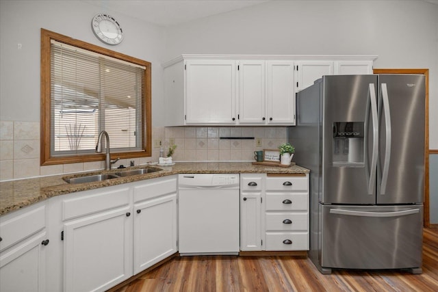 kitchen with stainless steel refrigerator with ice dispenser, sink, white dishwasher, light stone countertops, and white cabinets