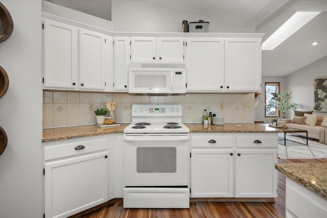 kitchen featuring vaulted ceiling with skylight, tasteful backsplash, white cabinetry, light stone countertops, and white appliances