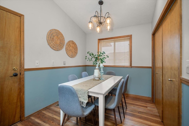 dining room with vaulted ceiling, dark hardwood / wood-style floors, and a chandelier