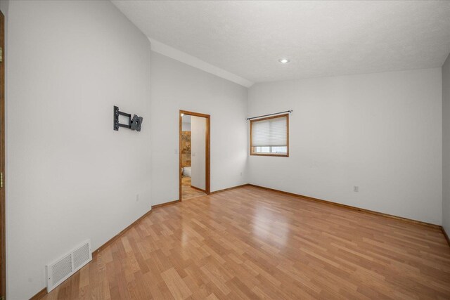 unfurnished room featuring lofted ceiling and light wood-type flooring