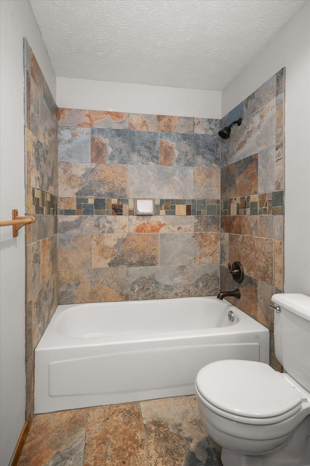 bathroom featuring tiled shower / bath, a textured ceiling, and toilet