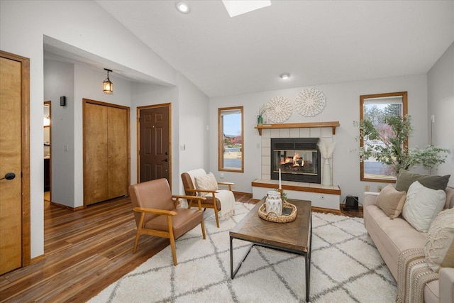 living room with a tile fireplace, lofted ceiling, and hardwood / wood-style floors