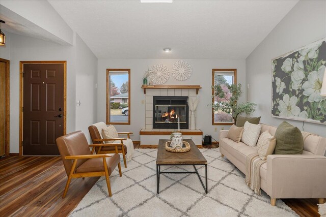 living room featuring lofted ceiling, a fireplace, and wood-type flooring