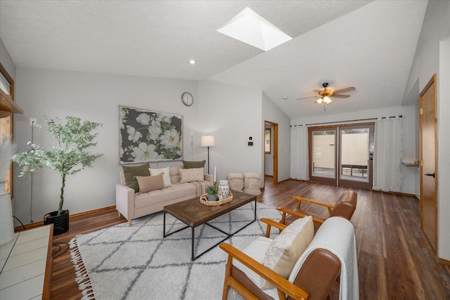 living room with ceiling fan, wood-type flooring, and lofted ceiling with skylight