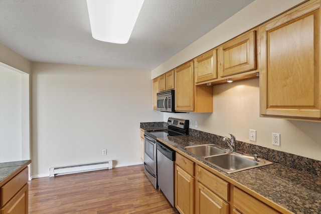 kitchen featuring dark wood-type flooring, sink, a textured ceiling, baseboard heating, and stainless steel appliances