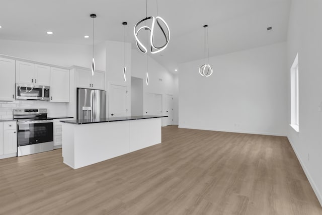 kitchen featuring pendant lighting, high vaulted ceiling, white cabinetry, a center island, and stainless steel appliances