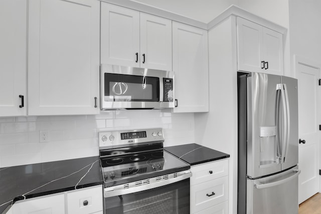 kitchen with dark stone countertops, backsplash, stainless steel appliances, and white cabinets