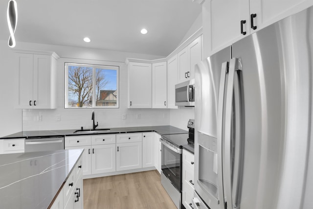 kitchen featuring sink, white cabinetry, backsplash, stainless steel appliances, and light hardwood / wood-style floors