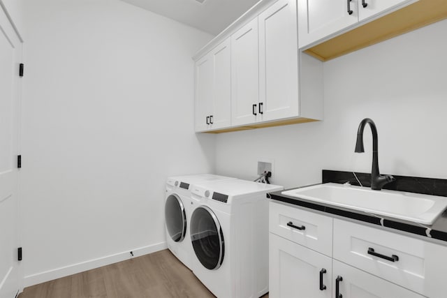 laundry area with washer and clothes dryer, sink, light hardwood / wood-style flooring, and cabinets