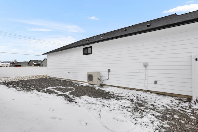 snow covered rear of property with ac unit