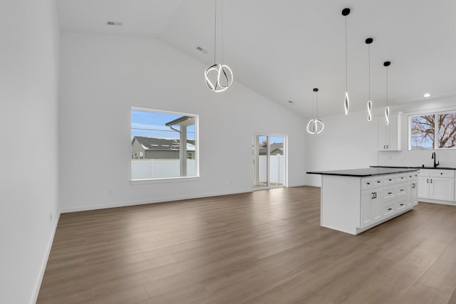 kitchen with pendant lighting, white cabinetry, high vaulted ceiling, and light hardwood / wood-style flooring