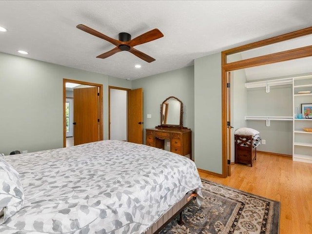 bedroom featuring ceiling fan, wood-type flooring, a spacious closet, and a closet