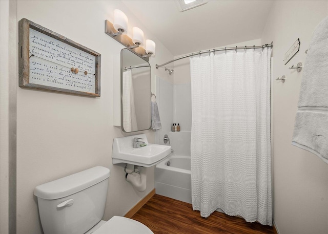 bathroom featuring hardwood / wood-style flooring, shower / bath combination with curtain, and toilet