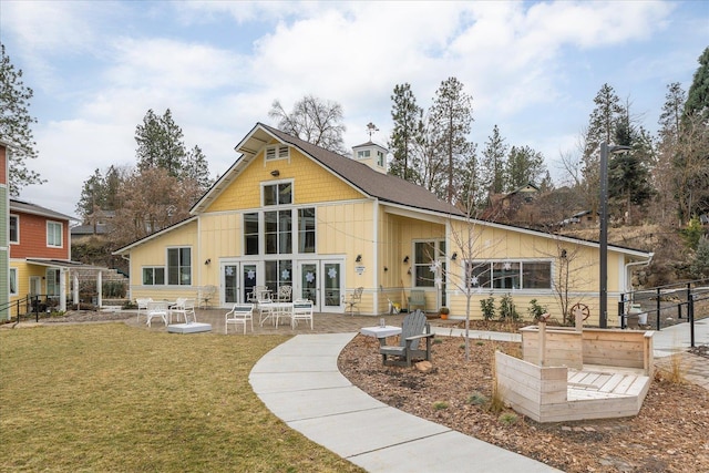 rear view of house featuring a lawn and a patio