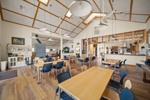 dining area with hardwood / wood-style flooring and high vaulted ceiling