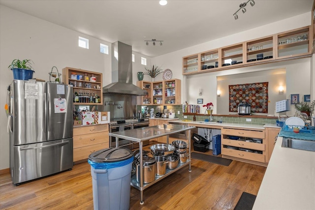 kitchen with light hardwood / wood-style flooring, appliances with stainless steel finishes, backsplash, extractor fan, and light brown cabinetry