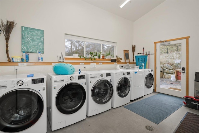 clothes washing area with a towering ceiling and washer and clothes dryer