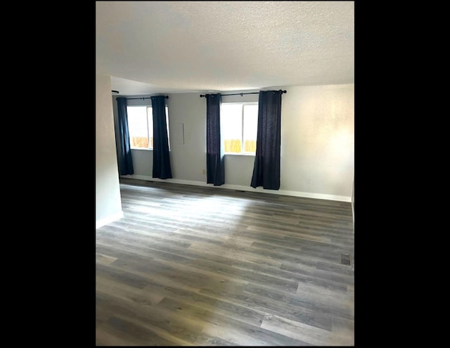 spare room featuring dark hardwood / wood-style floors and a textured ceiling