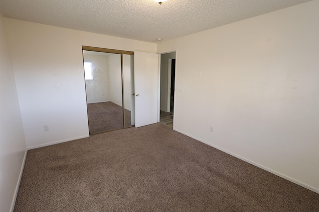 unfurnished bedroom featuring dark colored carpet, a textured ceiling, and a closet