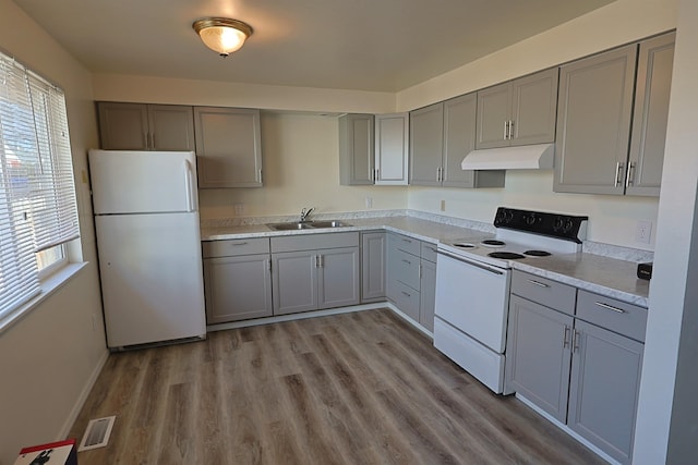 kitchen featuring sink, white appliances, gray cabinetry, light stone counters, and light hardwood / wood-style floors