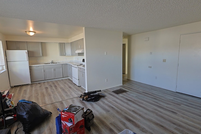 kitchen featuring gray cabinets, sink, white appliances, light hardwood / wood-style floors, and a textured ceiling