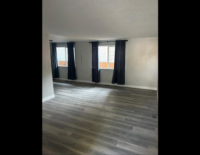 empty room with dark hardwood / wood-style floors and a textured ceiling