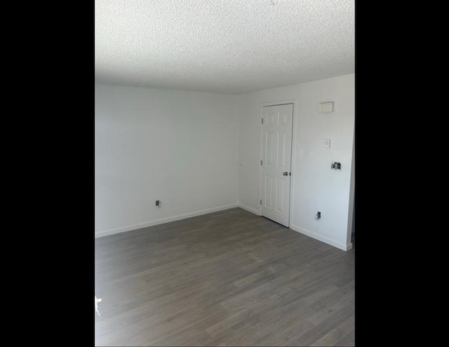 unfurnished room featuring dark wood-type flooring and a textured ceiling