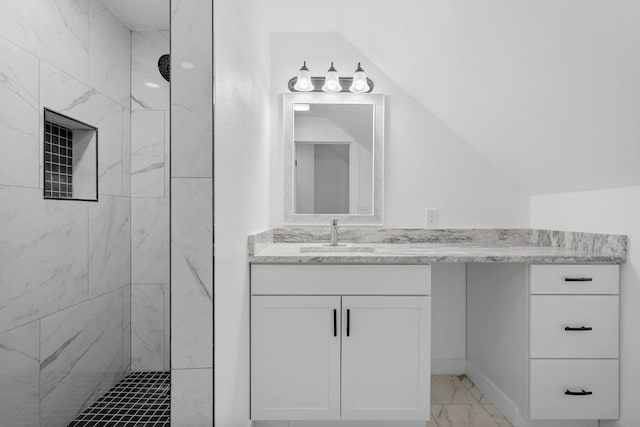 bathroom featuring vanity, vaulted ceiling, and a tile shower