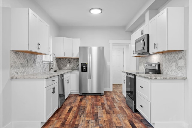 kitchen with white cabinetry, sink, light stone counters, stainless steel appliances, and dark wood-type flooring