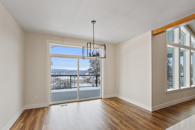 unfurnished dining area featuring a notable chandelier, dark wood-type flooring, and a mountain view