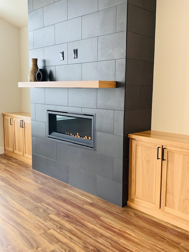 interior details with wood-type flooring and a tile fireplace