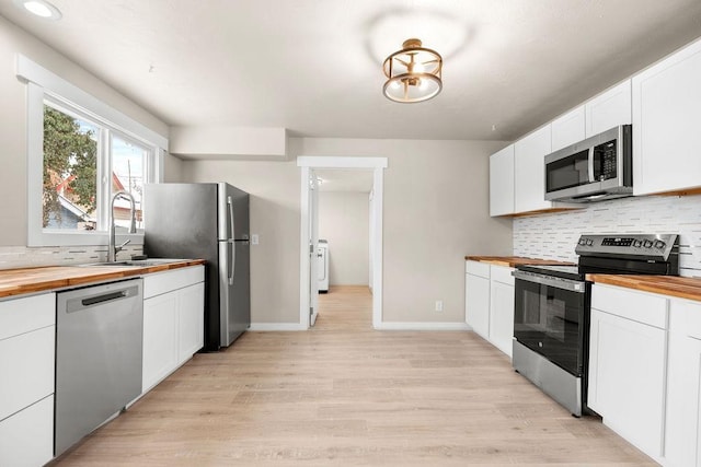 kitchen with white cabinetry, sink, wooden counters, decorative backsplash, and stainless steel appliances