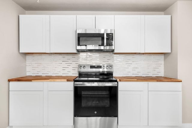 kitchen with white cabinetry, decorative backsplash, stainless steel appliances, and wooden counters