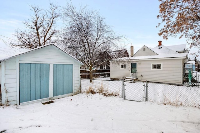 snow covered rear of property with an outdoor structure