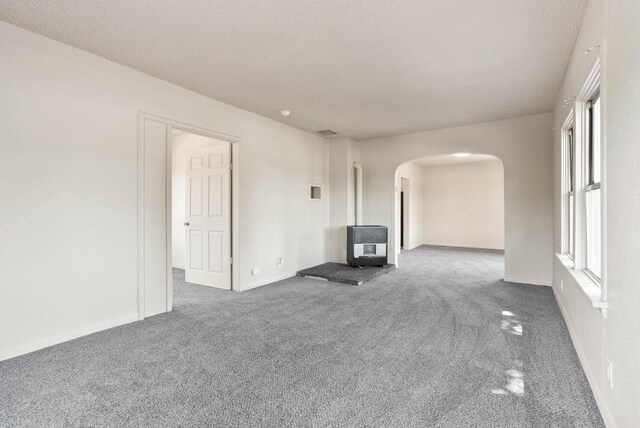 empty room featuring heating unit, a textured ceiling, and carpet