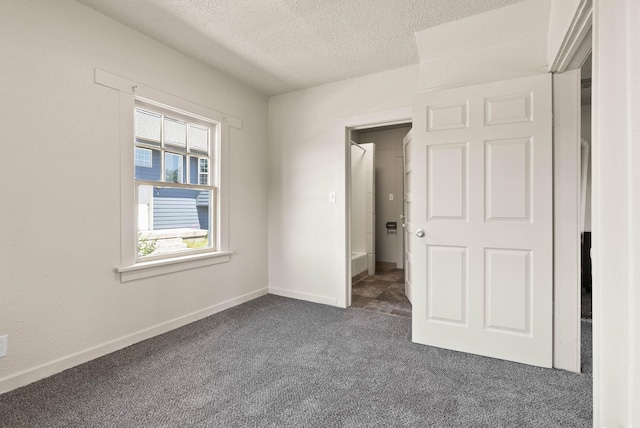 unfurnished bedroom featuring a textured ceiling and dark colored carpet