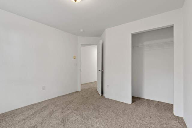 unfurnished bedroom featuring light carpet and a closet