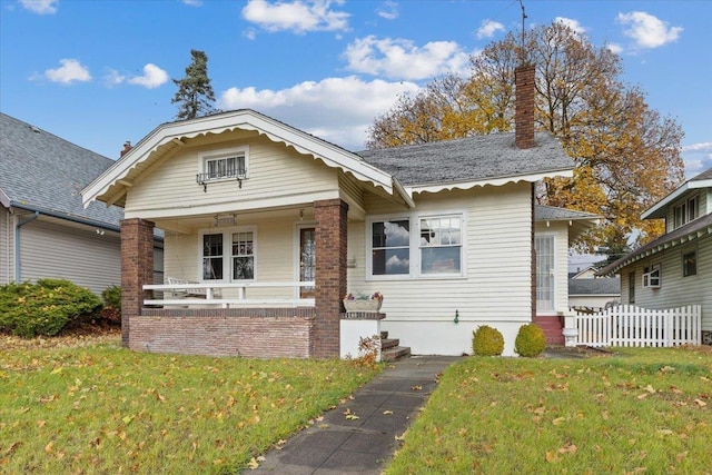 bungalow with covered porch and a front lawn