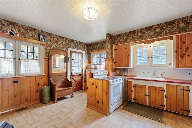 kitchen with light parquet flooring, sink, white electric range, and a textured ceiling