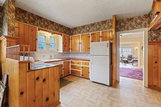 kitchen with white refrigerator, light parquet flooring, kitchen peninsula, and sink