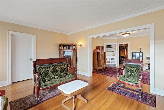 sitting room with crown molding and wood-type flooring