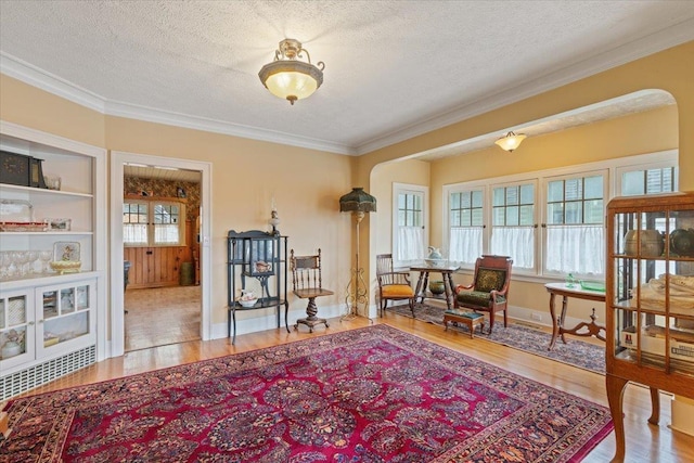 sitting room with ornamental molding, light hardwood / wood-style flooring, and a textured ceiling